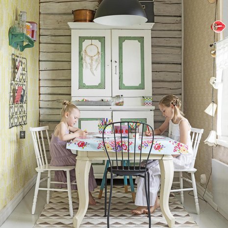 Huldan ja Thelman piirtelyhetki autiotalosta pelastetun pöydän ääressä. Kaappi, jossa säilytetään askartelutarvikkeita, on kirpputorilöytö.