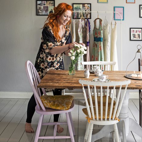 Maria Kalmi asuu puutalon yläkerrassa Porvoossa. Ruokailutila toimii myös mekkojen myymälänä. Ruokapöytä on vanha ovi, jonka jalan Maria sai ilmaiseksi. Tuolit hän sai mummiltaan.