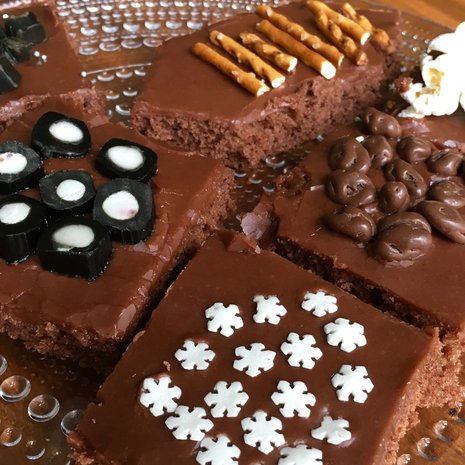 Mokkapalojen tasainen kuorrutus on mahtava pinta erilaisille koristeille. Kuvan mokkapaloissa on käytetty salmiakkitoffeeta, lakupaloja, suolatikkuja, popcornia, suklaarusinoita ja koristerakeita.