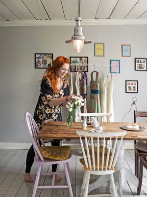 Maria Kalmi asuu puutalon yläkerrassa Porvoossa. Ruokailutila toimii myös mekkojen myymälänä. Ruokapöytä on vanha ovi, jonka jalan Maria sai ilmaiseksi. Tuolit hän sai mummiltaan.