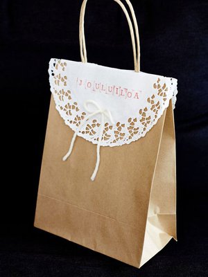 Tavallisesta paperipussista tulee juhlava, kun sen koristaa kakkupaperilla ja villalankarusetilla. Hyvän joulun toivotus on tehty kirjainleimoilla.