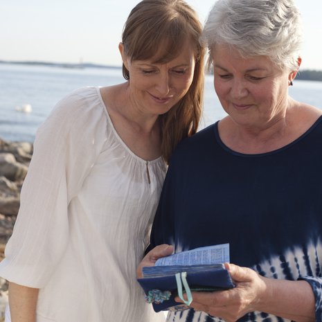 Päivi Kanervan (oik.) mukana kulkee pieni albumi, johon hän on koonnut kuvia lapsistaan. Vasemmalla psykoterapeutti Merja Miesvirta.