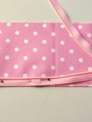 Asettele ja neulaa vetoketju paikoilleen oikeat puolet vastakkain, jolloin lukko on kangasta vasten. Vetoketjun ura asettuu kappaleen reunaan ja nauhaosa saumanvaraan.