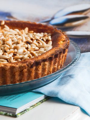 Italialainen sitruunapiiras viimeistellään pinjansiemenillä. 