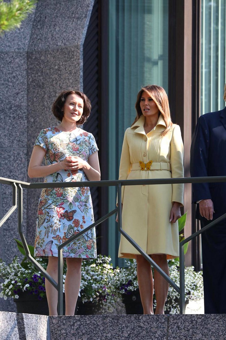 Presidenttien puolisot Jenni Haukio ja Melania Trump Mäntyniemen parvekkeella. Andiata tiedotti ylpeänä, että Jennin asu oli heidän mallistostaan. Helsingin Sanomien mukaan virkasiskon asu oli puolestaan Guccin, perhonen vyön solkena. 