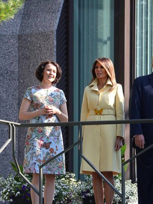 Presidenttien puolisot Jenni Haukio ja Melania Trump Mäntyniemen parvekkeella. Andiata tiedotti ylpeänä, että Jennin asu oli heidän mallistostaan. Helsingin Sanomien mukaan virkasiskon asu oli puolestaan Guccin, perhonen vyön solkena. 