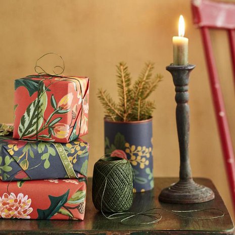 Tänä vuonna kuusen alta pilkottaa täyteläisiä värejä ja kukkakuoseja. Kuusiruukku syntyi päällystämällä peltipurkki lahjapaperilla. Rifle Paper -kukkapaperit Papershop, paperinaru Askarelli, peltipöytä Moko ja kynttilänjalka Mosa Interiors.