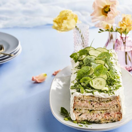 Koristele voileipäkakku näyttäväksi hienonnetulla ruohosipulilla, kurkkulastuilla ja sitruunamelissalla.