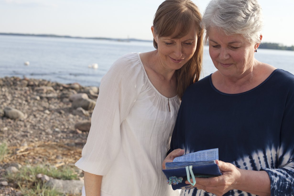 Päivi Kanervan (oik.) mukana kulkee pieni albumi, johon hän on koonnut kuvia lapsistaan. Vasemmalla psykoterapeutti Merja Miesvirta.