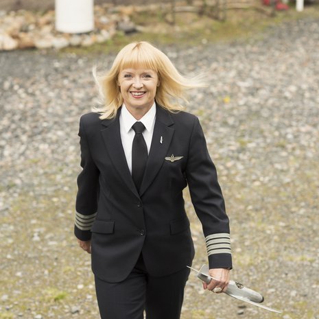 Maritsa Lindroos, 48, kotipihassa Laihialla tänä kesänä. Päällä lentokapteenin työasu, kädessä isän tekemä lentokone ajalta, jolloin tytöistä ei tullut lentäjiä.