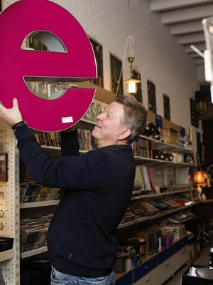 Esa Salminen, 55, pitää kirpputori Kisälliä Lahden Sopenkorvessa, ja hänen perheeseensä kuuluvat vaimo ja kaksi aikuista lasta. E-kirjaimen Esa osti mieheltä, joka purkaa vanhoja valomainoksia. Myyntiin menee.