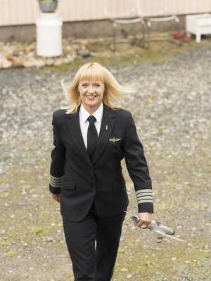 Maritsa Lindroos, 48, kotipihassa Laihialla tänä kesänä. Päällä lentokapteenin työasu, kädessä isän tekemä lentokone ajalta, jolloin tytöistä ei tullut lentäjiä.