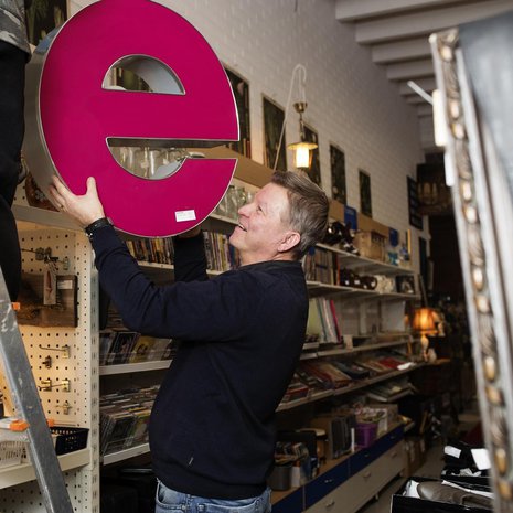 Esa Salminen, 55, pitää kirpputori Kisälliä Lahden Sopenkorvessa, ja hänen perheeseensä kuuluvat vaimo ja kaksi aikuista lasta. E-kirjaimen Esa osti mieheltä, joka purkaa vanhoja valomainoksia. Myyntiin menee.