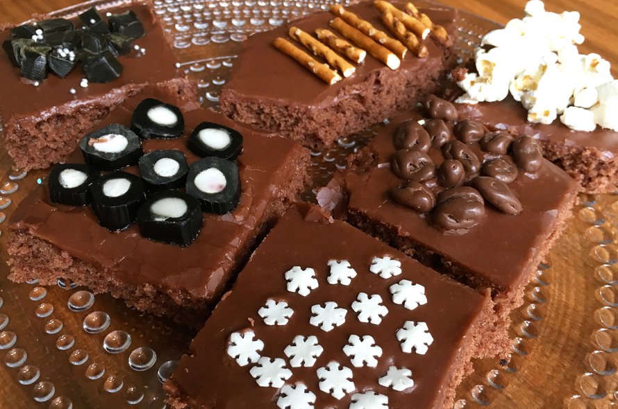 Mokkapalojen tasainen kuorrutus on mahtava pinta erilaisille koristeille. Kuvan mokkapaloissa on käytetty salmiakkitoffeeta, lakupaloja, suolatikkuja, popcornia, suklaarusinoita ja koristerakeita.